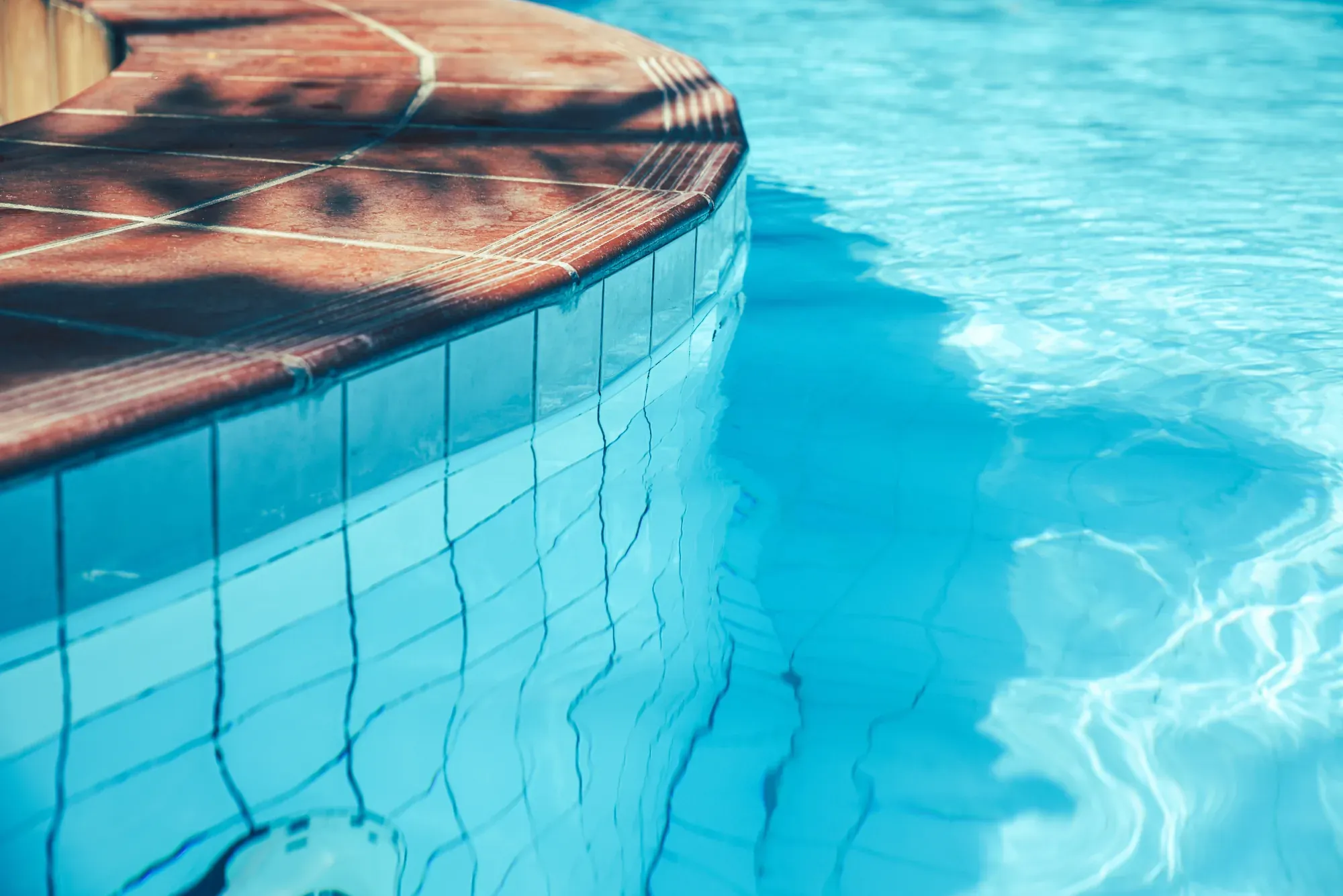 Curved edge of an open-air pool with turquoise water