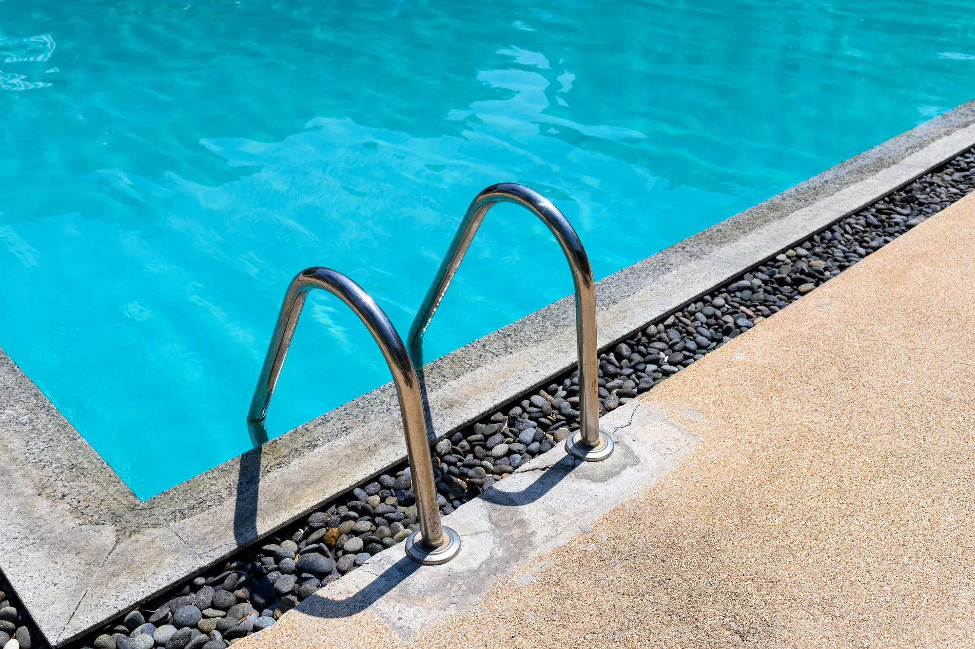 Overhead view of a pool ladder and handrail beside the deck