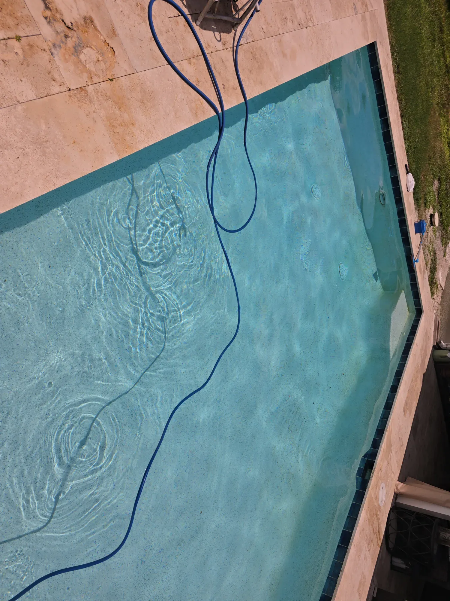 Overhead view of a pool with the cleaning hose in the water