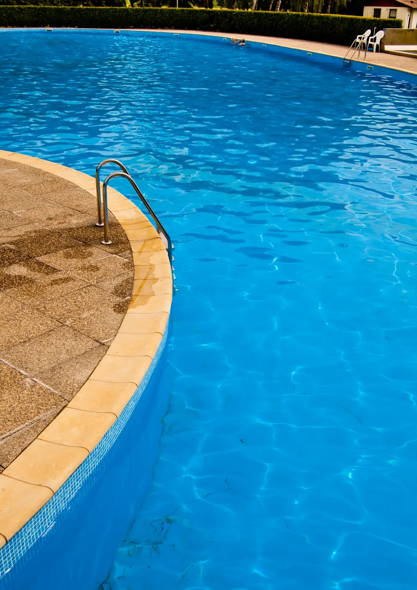 Pool ladder and clear blue water in late afternoon light