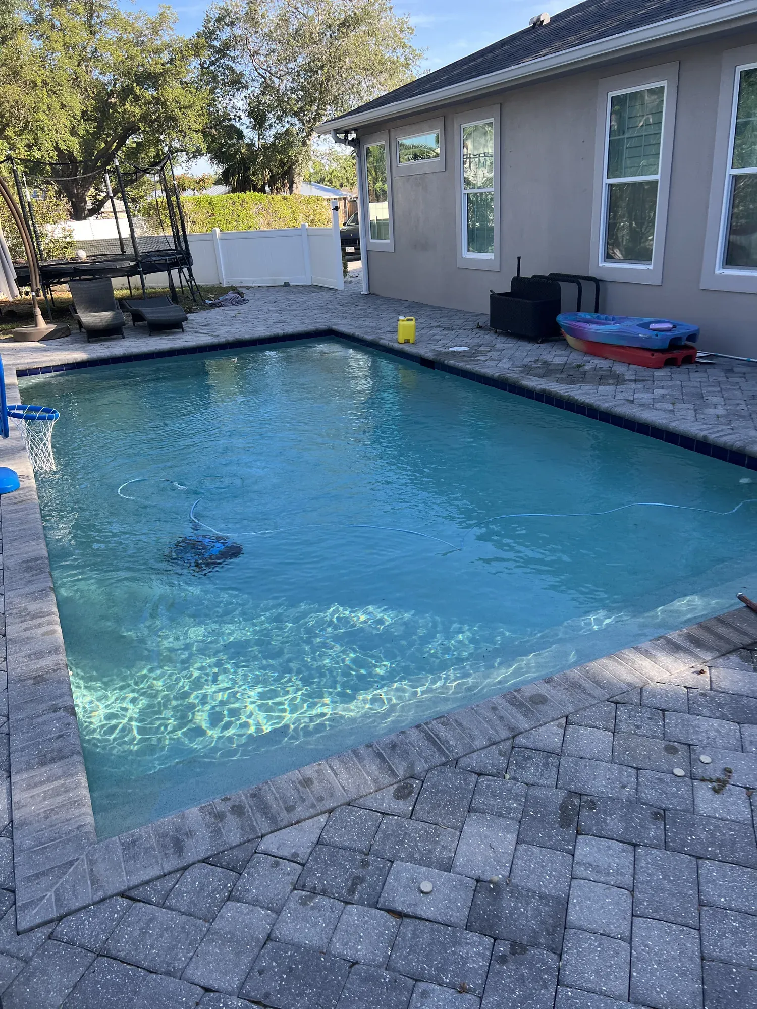 Robotic pool cleaner and service supplies beside the pool deck