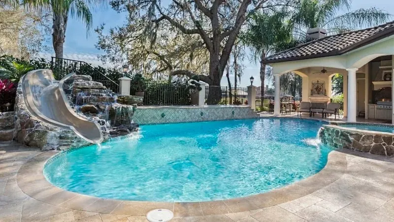Rock waterslide feature beside a screened pool and guest house