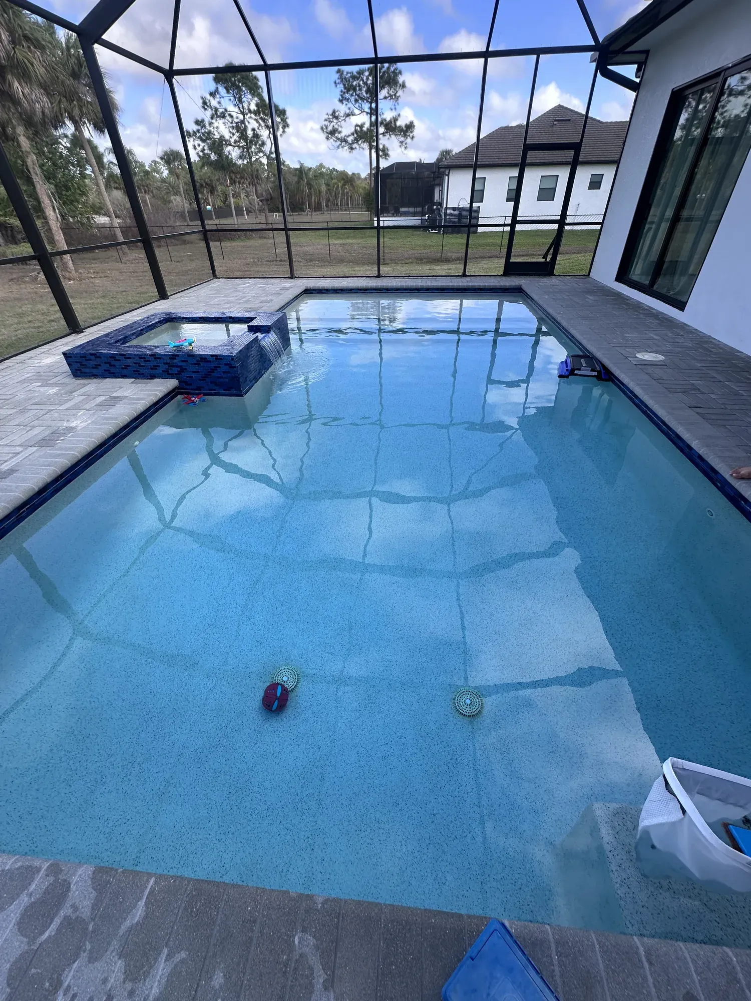 Screened pool and spa with cleaning tools ready at the water's edge