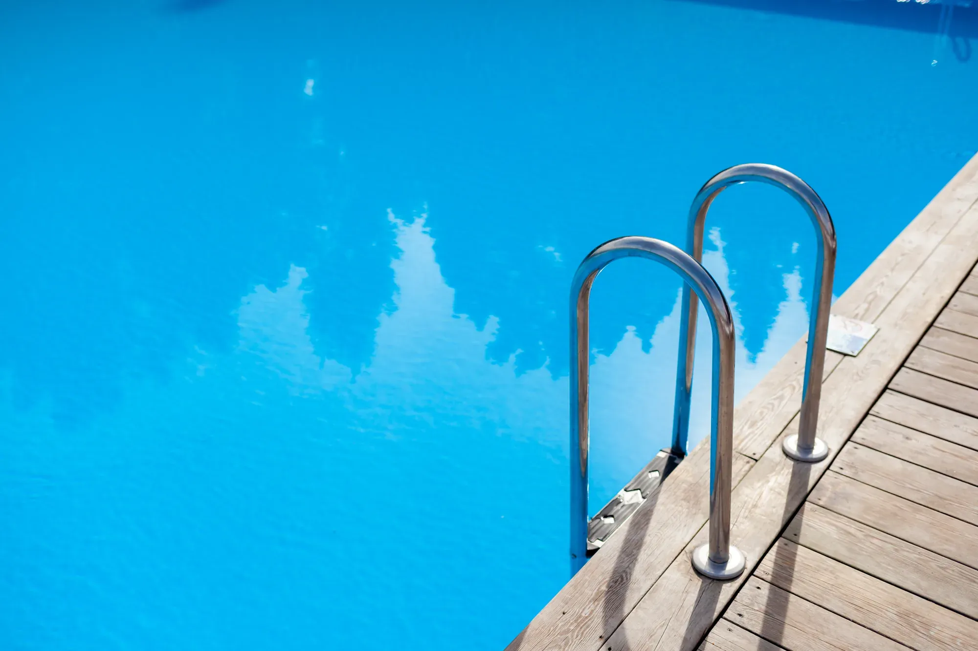 Pool stair handrail against a wooden deck