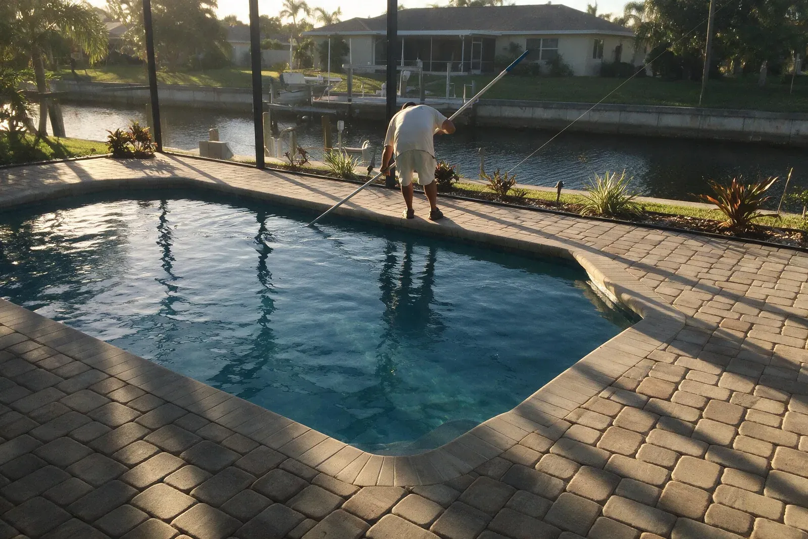 Technician working along the edge of a canal-front pool